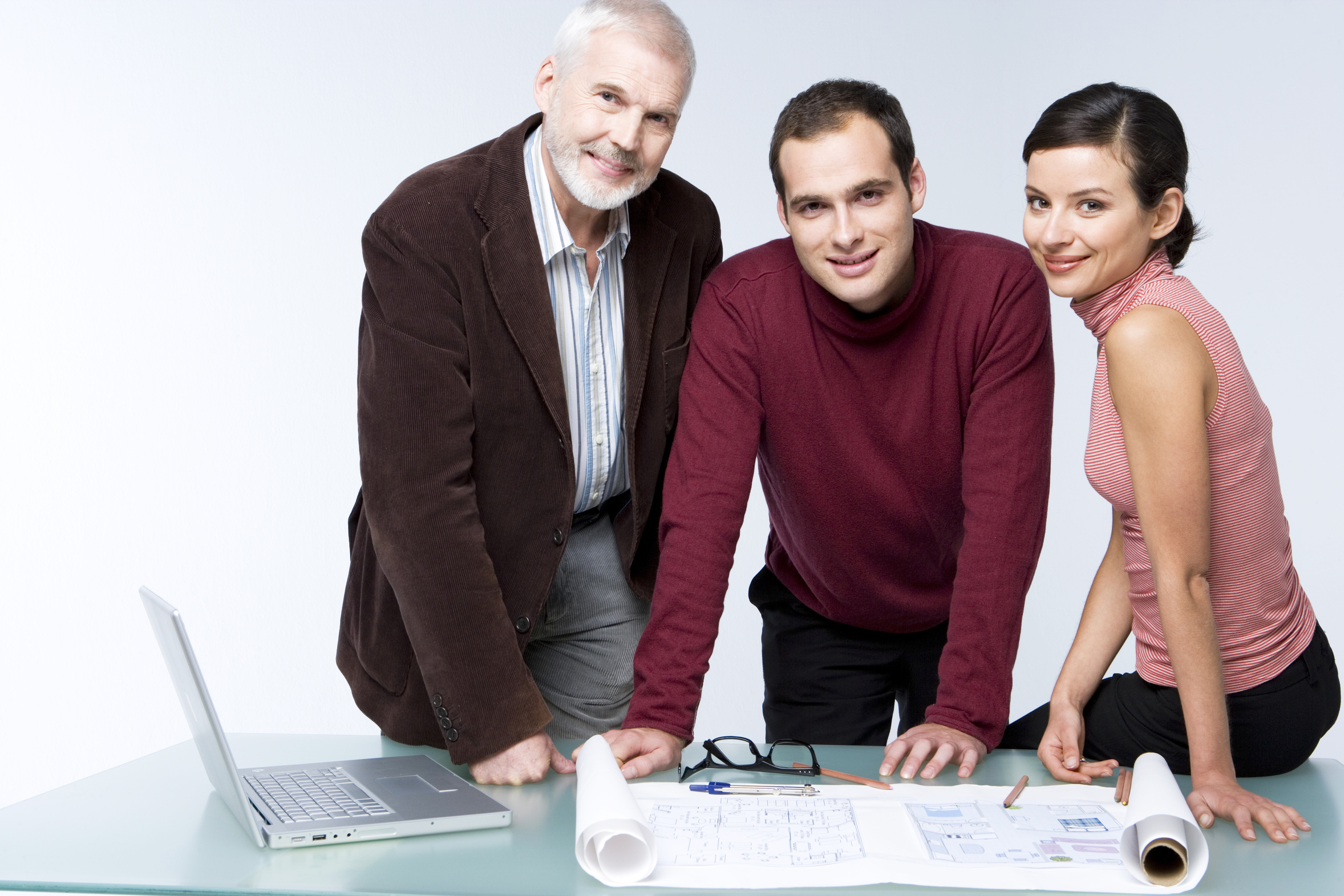 Eine Frau und zwei Männer stehen gemeinsam vor einem Plan.